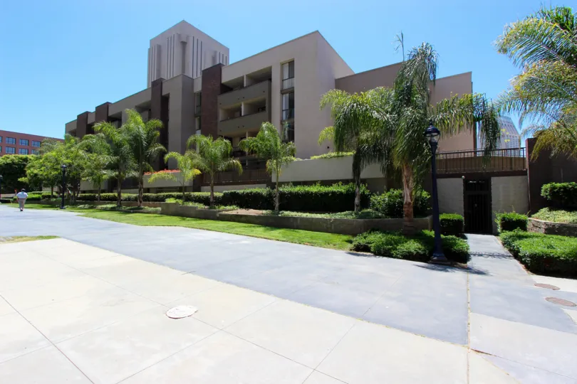 A view of a garden with palm trees outside a building at Marina Park, San Diego, on a clear and sunny day.