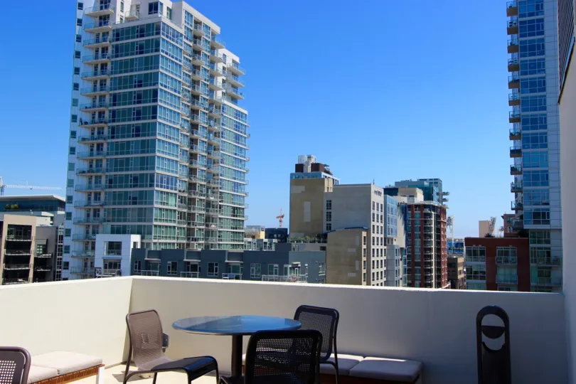 View of a patio with four chairs and padded benches with a view of buildings in the background