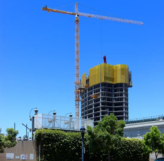 A tall crane being used in the constructions of a building in Pacific Gate on a beautiful day.