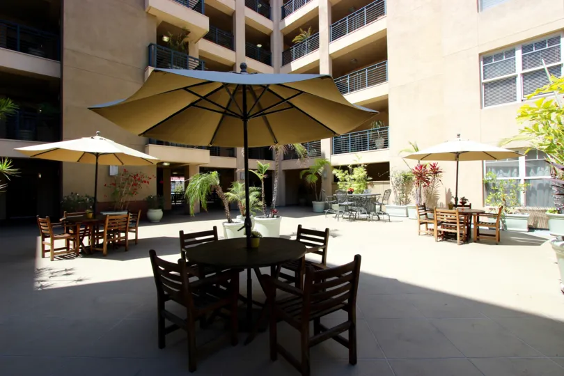 Tables and chairs with umbrellas at a plaza at Pacific Terrace in downtown San Diego, CA