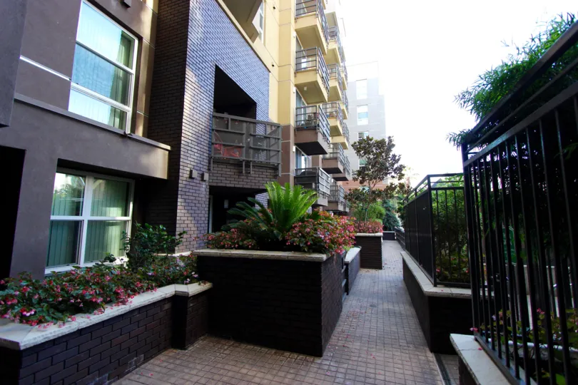 Brick road lined with flower planters and a black iron fence at Park Blvd East in Downtown San Diego CA