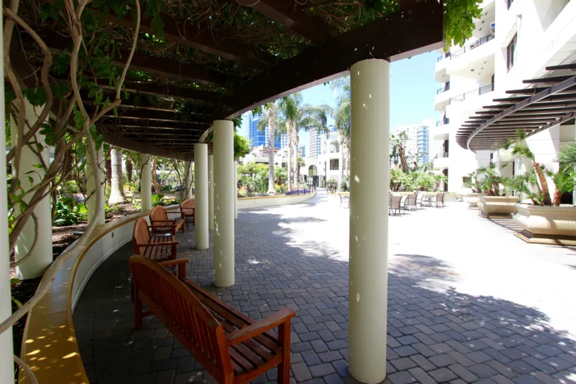 A shaded corridor bordering a park next to a residential building.
