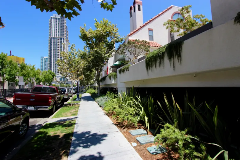 A red pickup truck is parked on the street near the Park Row condos