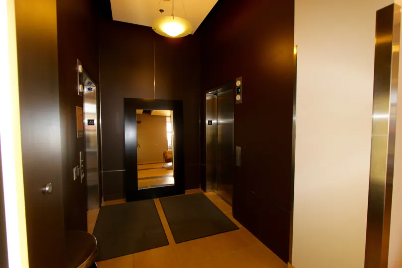 Two elevators inside of a brown lobby near a light at Park Terrace inside Downtown San Diego CA
