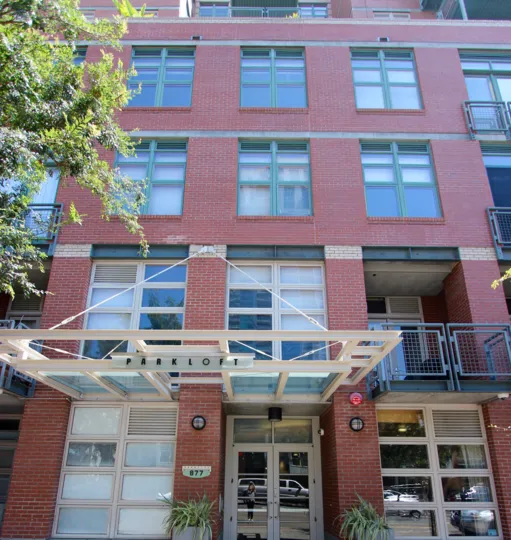 A sunlit and brilliant day at The Parkloft with a view of the exterior of the gorgeous red colored building with its well designed windows and beautiful entrance