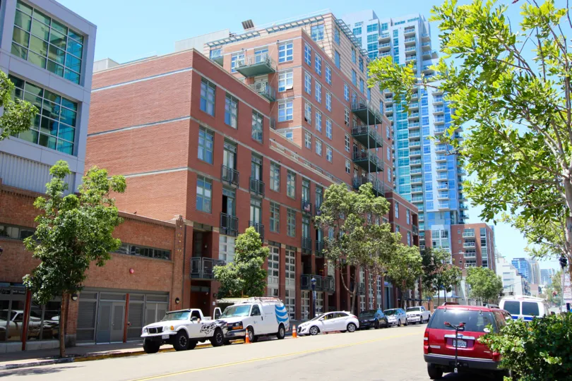 A sunilt and bright morning with a view of the red colored modern Parkloft building with tree-lined street with parked cars
