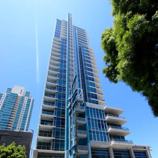Clear blue skies at Sapphire Tower with another tall building and tree.