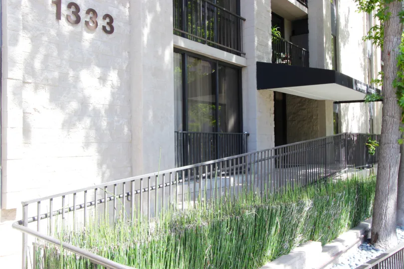 Gray iron fence lined with plants in front of Symphony Terrace at Downtown San Diego CA