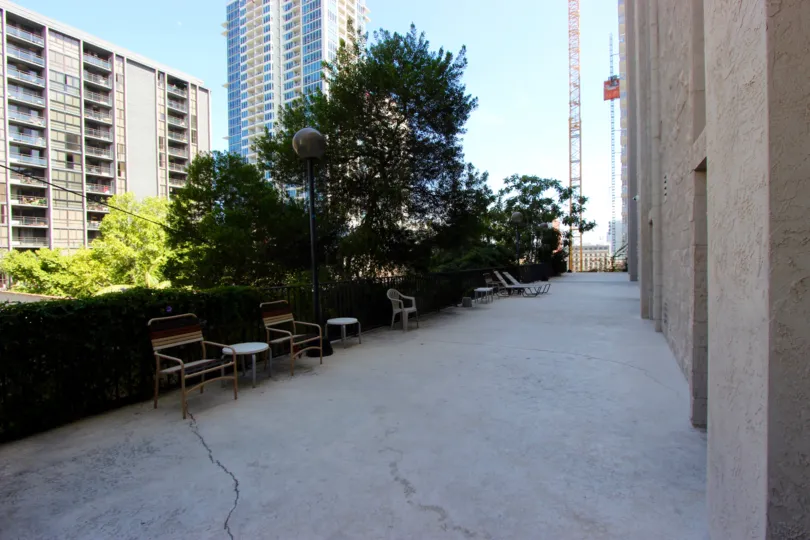 A sunny day in the area of Symphony Terrace, sidewalk, outside, tree, chair, table, highrise