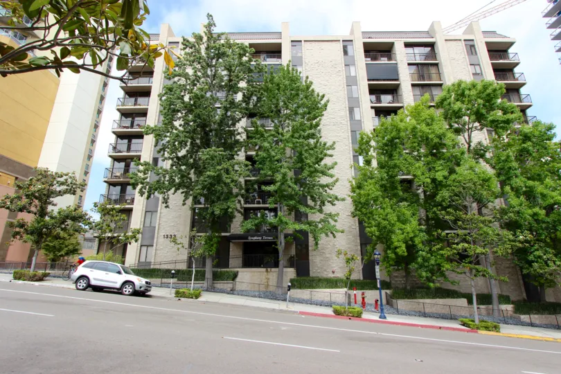 Trees before white buildings in Symphony Terrace neighborhood