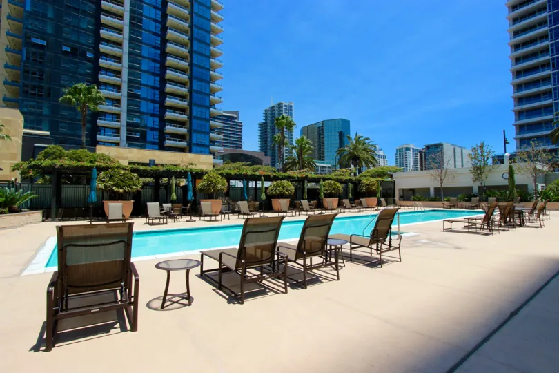 A pool with beach chairs surrounded by buildings in The Grande neighborhood