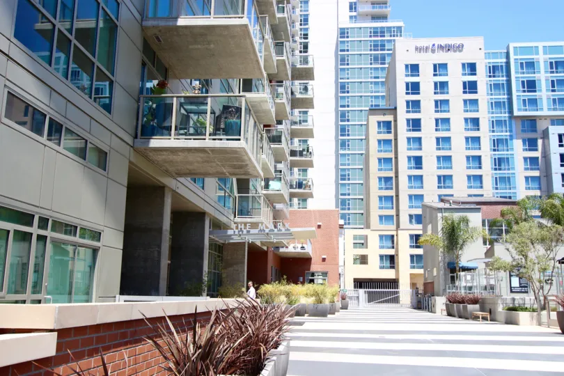 A sunny day in the area of The Mark, balcony, stairs, brick, windows, high rise condos, trees, potted plants