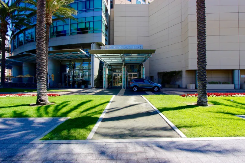 A sidewalk and a green lawn before a building in The Metropolitan neighborhood