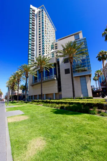 A warm and sunny day with the street view showcasing the modern architecture of the massive building of The Metropolitan with Palm tree lined streets