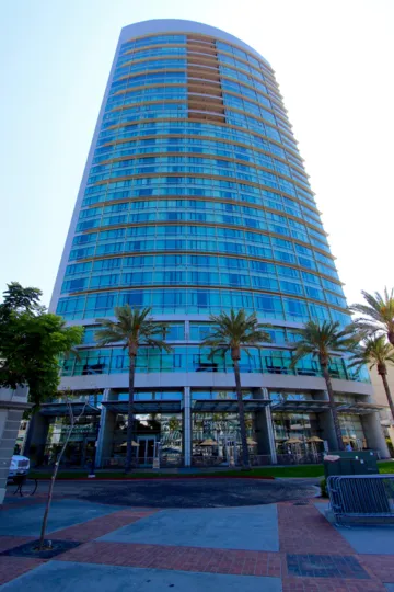 The exterior of the Metropolitan with palm trees and lots of windows in downtown San Diego