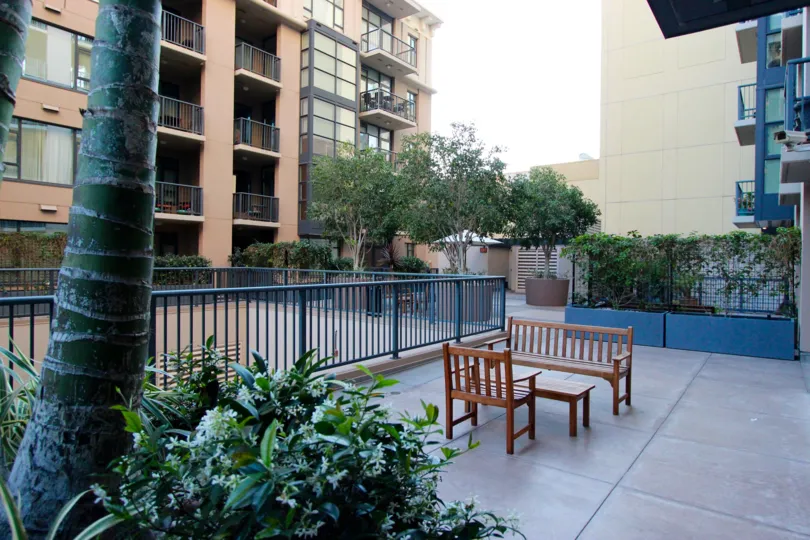 A sunny day in the area of Trellis, outside, fence, table, chair, bench, tree, balcony