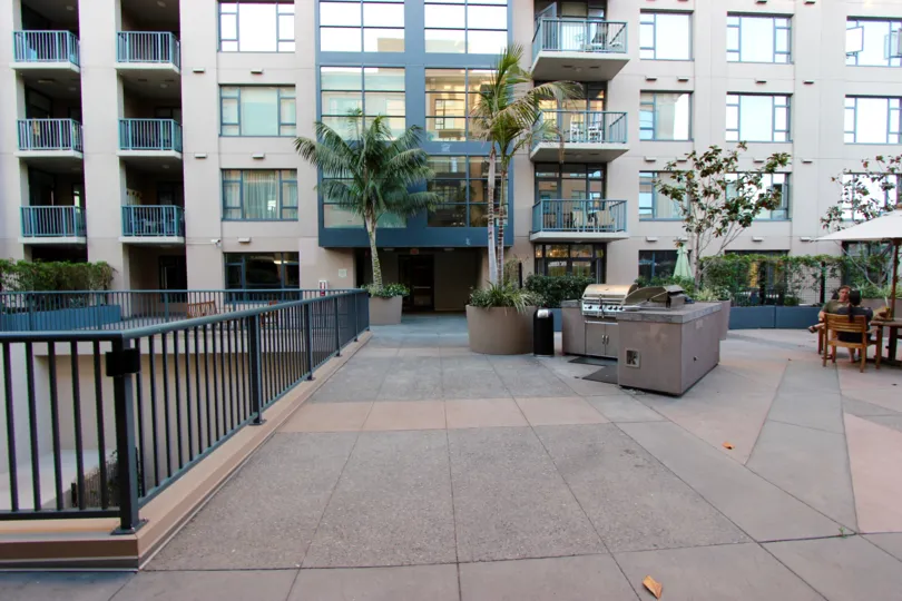 Rooftop patio with BBQ and furniture beneath even taller buildings at Treillis in Downtown San Diego CA