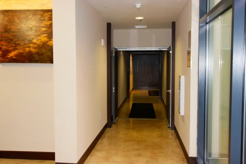 Hallway with art, soft lighting, and large entry doors at Trellis in Downtown San Diego, California