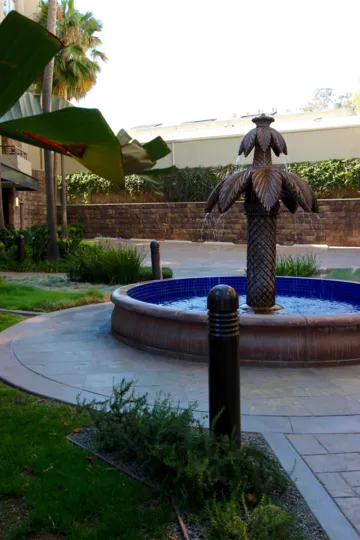 A sunny day in the area of Union Square, outside, fountain, palm trees, brick wall, roof