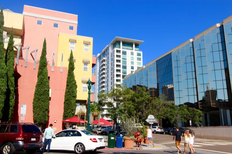 Tall pine trees sit outside of a pink, salmon, and yellow building at Village Walk