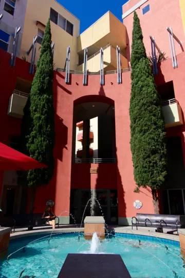 The fountain outside of Village a Walk with two tall trees in downtown San Diego