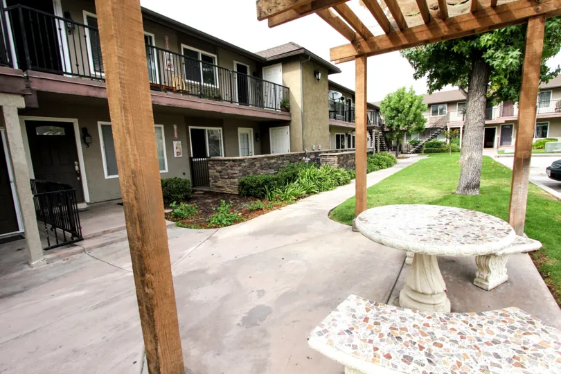The arbors in Oakdale California. Are made out of wood. They have white Chairs and tables under them.
