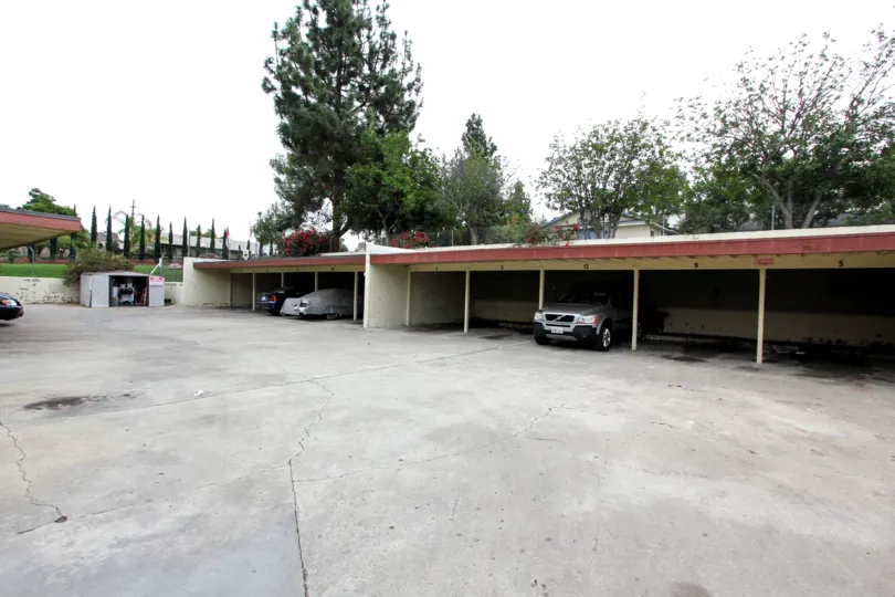 A cloudy day overlooking garage with parked cars and trees.