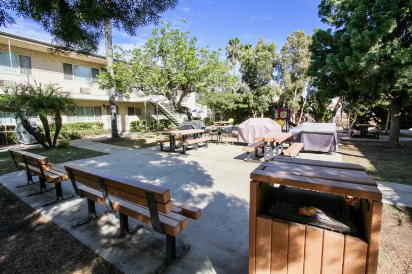 Park with brown wood benches in front of an apartment complex