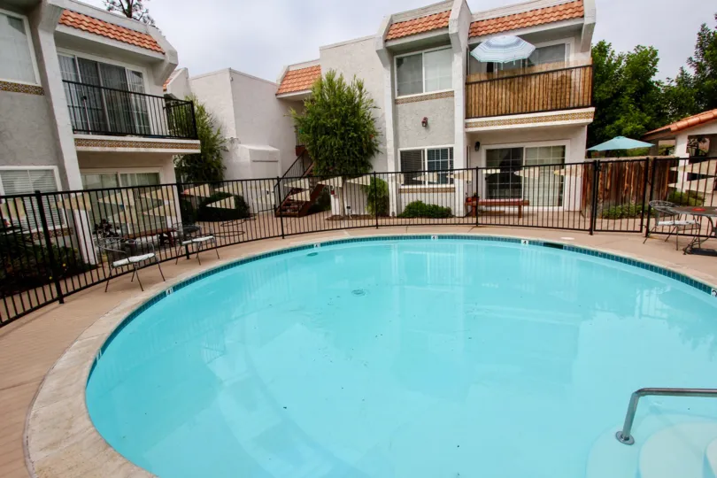 VERY BEAUTIFUL HOUSE. IN FRONT OF IT THERE ARE FOUR SMALL TREES. AND THERE IS A ROAD, VERY CLEAN. AND THERE IS A POOL.