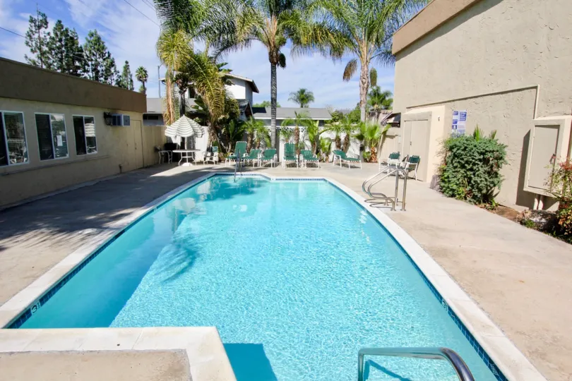 Swimming pool with lawn chairs and clubhouse at Mollison Estates in El Cajon California