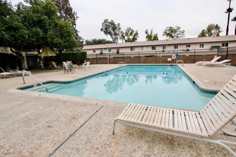 VERY BEAUTIFUL HOUSE. IN FRONT OF IT THERE ARE FOUR SMALL TREES. AND THERE IS A ROAD, VERY CLEAN. AND THERE IS A POOL.