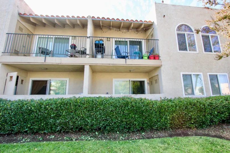 A view of the balcony of several apartments of the Monterra Community in El Cajon, CA on a sunny day surrounded by bushes.