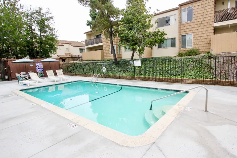 VERY BEAUTIFUL HOUSE. IN FRONT OF IT THERE ARE FOUR SMALL TREES. AND THERE IS A ROAD, VERY CLEAN. AND THERE IS A POOL.