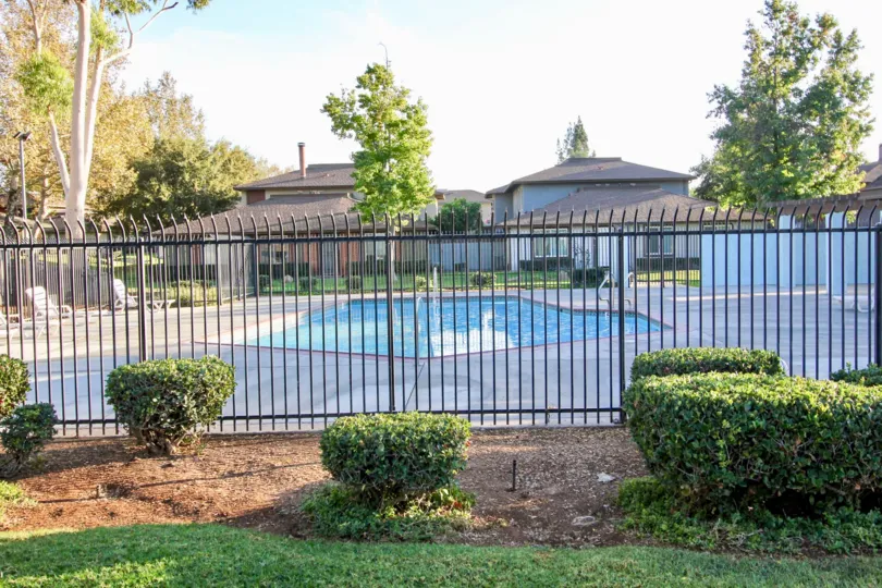 VERY BEAUTIFUL HOUSE. IN FRONT OF IT THERE ARE FOUR SMALL TREES. AND THERE IS A ROAD, VERY CLEAN. AND THERE IS A POOL.
