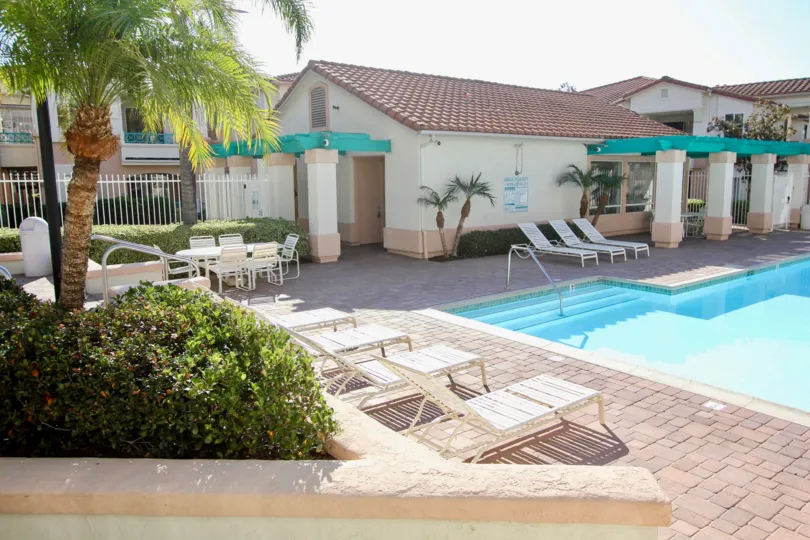 VERY BEAUTIFUL HOUSE. IN FRONT OF IT THERE ARE FOUR SMALL TREES. AND THERE IS A ROAD, VERY CLEAN. AND THERE IS A POOL.