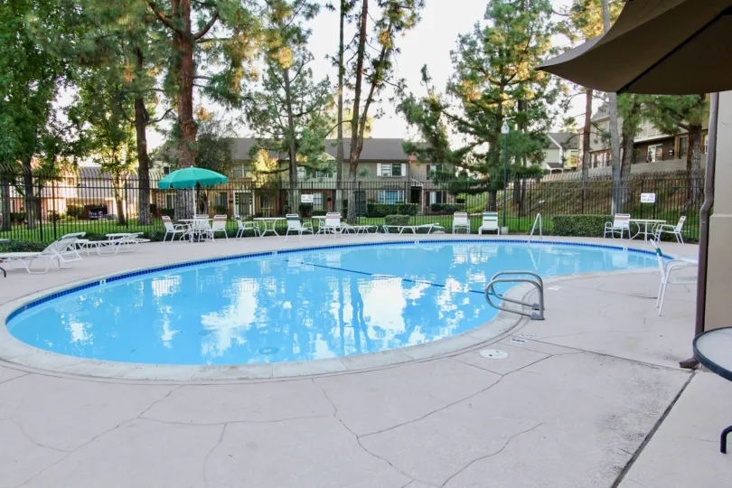 VERY BEAUTIFUL HOUSE. IN FRONT OF IT THERE ARE FOUR SMALL TREES. AND THERE IS A ROAD, VERY CLEAN. AND THERE IS A POOL.