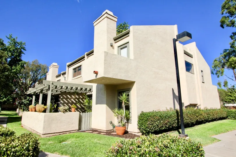 A sandy house with some bushes and a lamp on the side during a sunny day in Sunshine Shadows, El Cajon, CA