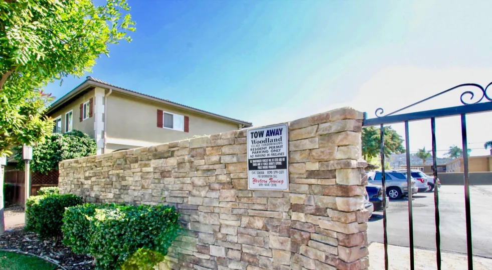 Brick wall with black iron gate and parking at Woodland Village in El Cajon CA