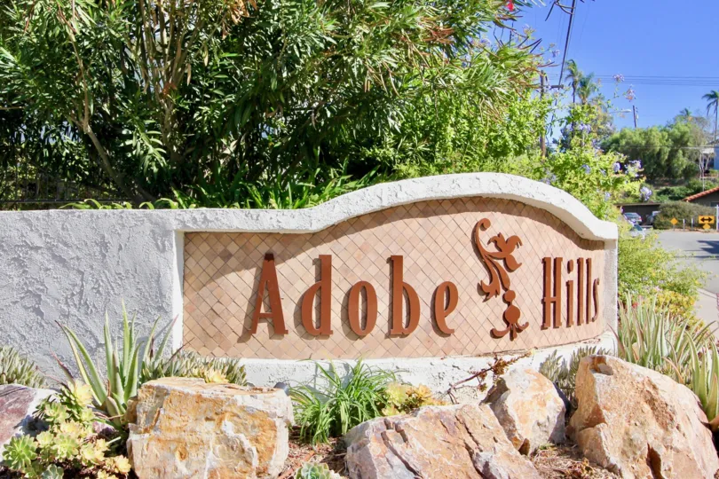The neighborhood sign the Adobe Hills community on a sunny day of with surrounding shubbery