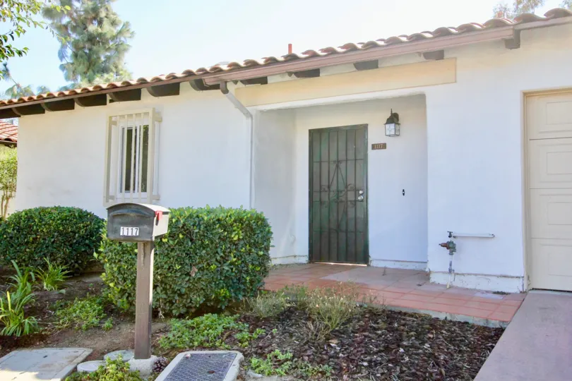 A Buena Ventura, California home with white plaster exterior, terra cotta shingles, beautiful landscaping, garage and more