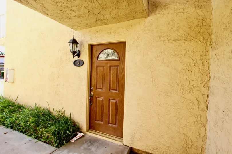 Hampton Place, Escondido, California - A beautiful wood door in a plaster wall with lantern style lighting