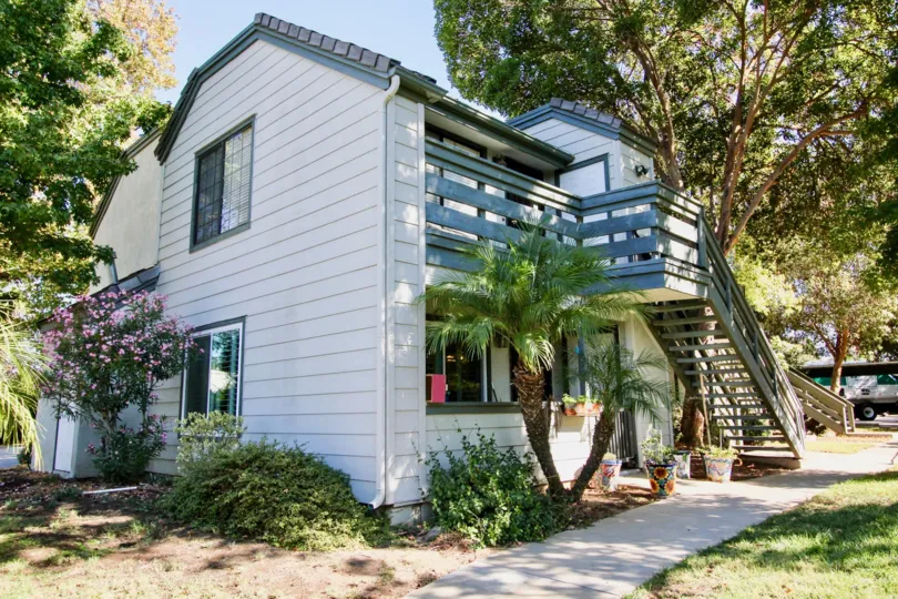 A split level home with white siding, blue deck and staircase in Hidden Glen, Escondido California