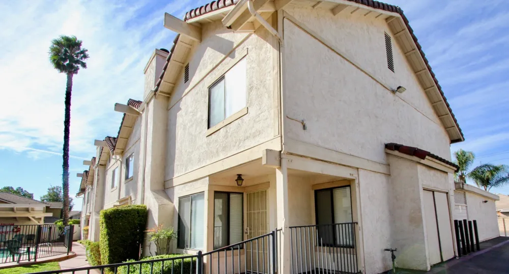 A few townhomes next to the pool area and palm tree in Martin Court Gardens