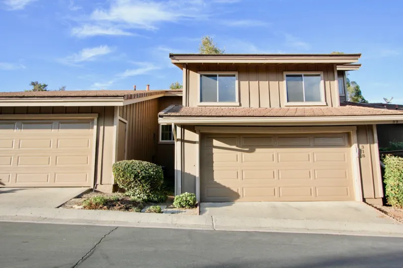 Two storey attached home with double car garage on a gentle slope and well maintained shrubs in Morningside Woods