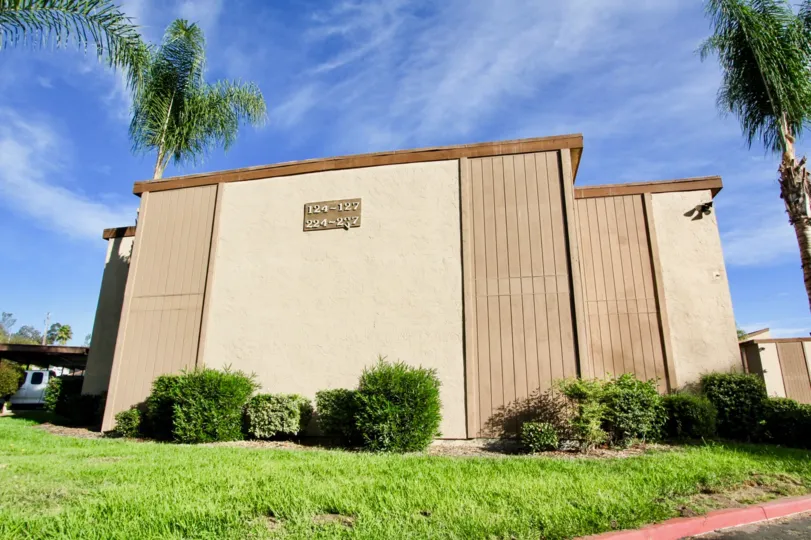The side view of a building with trees and shrubs on a sunny day in Rock Springs West community of Escondido, California