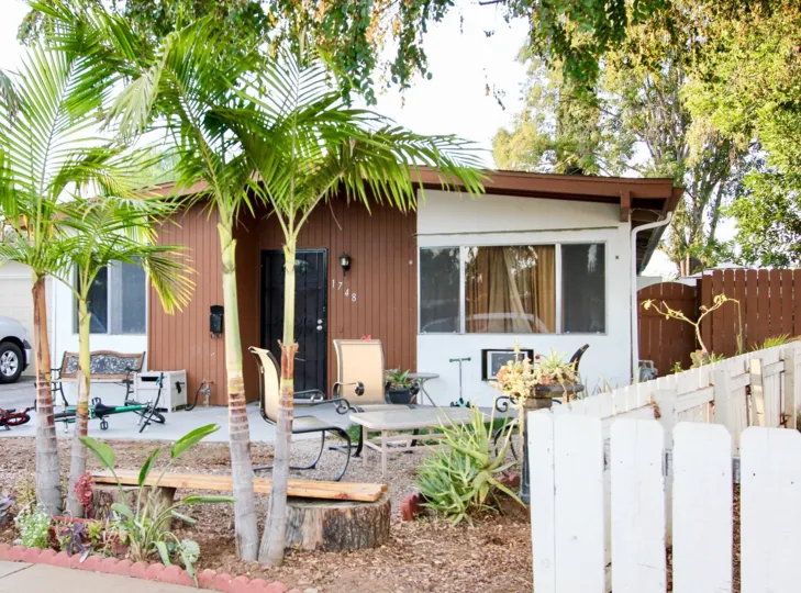 Palm trees and chairs before a small house in Rosedale Manor neighborhood