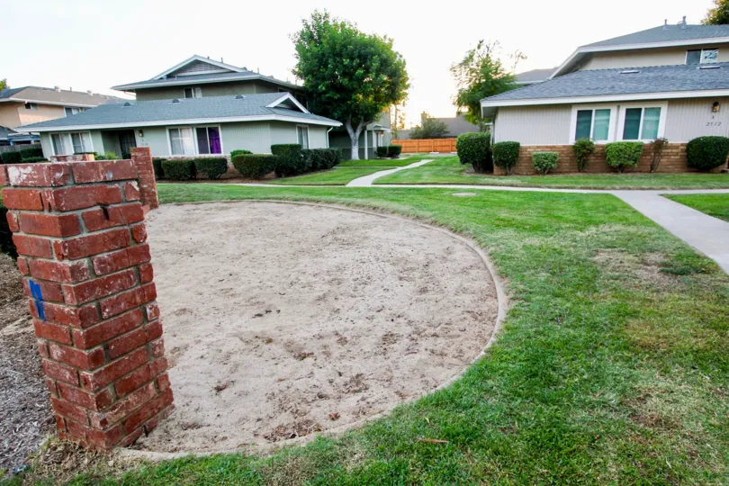 THE BUNGALOW IN THE SHADOW MOUNTAIN WITH THE GRASSLAND, BRICKS WALL, PLANTS, TREE