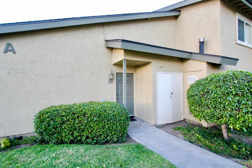 Sienna Hills 101 House A, Gray Door with Tan outside, 2 shrubs outside.