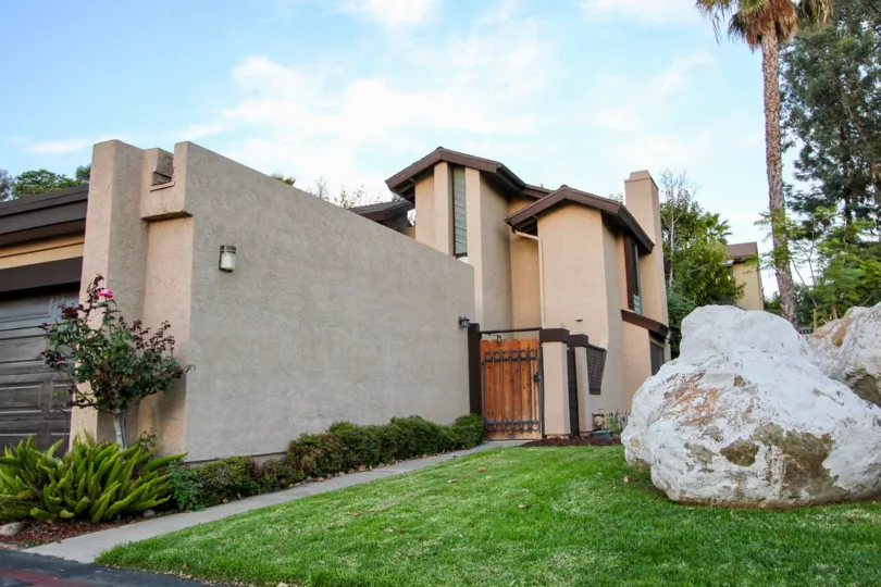 Large boulders on a lush green yard near a security gate at Skylark Terrace in Escondido California