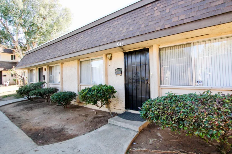 One story yellow house with sidewalk and shingled roof, in Villa Grande, Escondido, California.